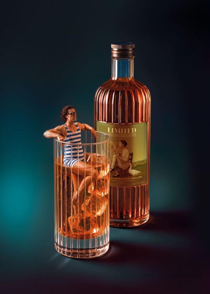 Un uomo in costume d’epoca seduto dentro un bicchiere di whisky accanto alla bottiglia