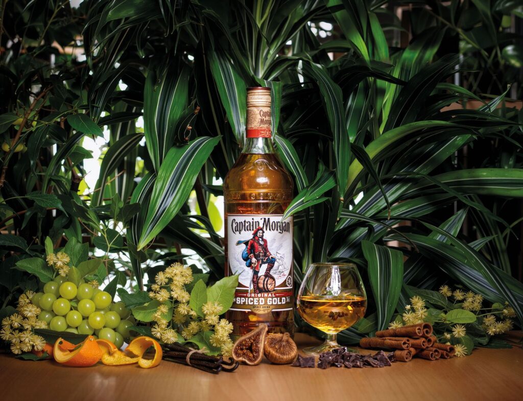 Bottiglia di rum speziato tra piante tropicali, con fichi, vaniglia, cannella e cioccolato